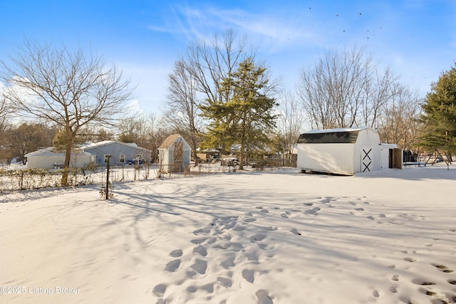 snowy yard featuring a shed