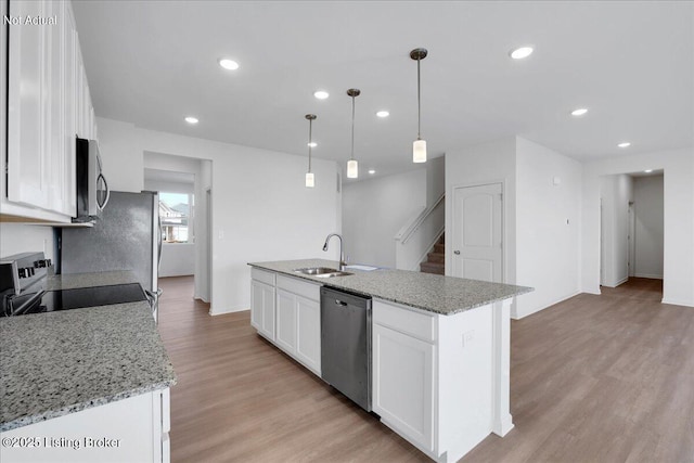 kitchen featuring sink, white cabinetry, decorative light fixtures, stainless steel appliances, and a kitchen island with sink