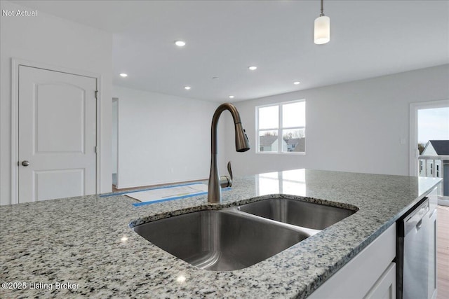 kitchen with decorative light fixtures, dishwasher, sink, white cabinets, and light stone countertops