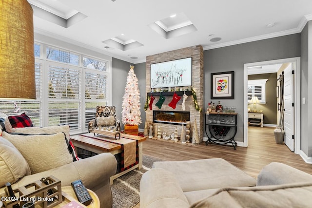 living room featuring ornamental molding, coffered ceiling, light wood-type flooring, and a stone fireplace