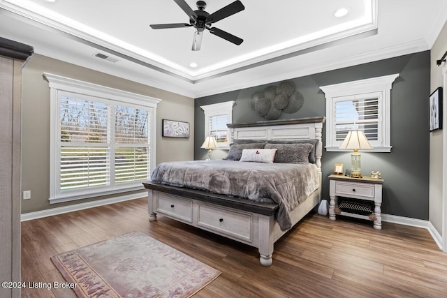 bedroom featuring ceiling fan, hardwood / wood-style floors, ornamental molding, and a raised ceiling