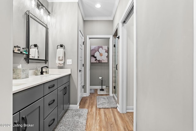 bathroom with hardwood / wood-style floors, ornamental molding, a shower with shower door, and vanity