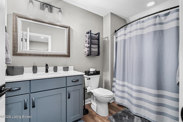 bathroom with toilet, vanity, and hardwood / wood-style floors