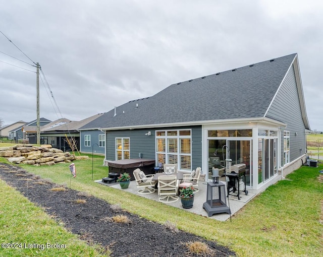 rear view of house with a lawn, a patio area, and a hot tub