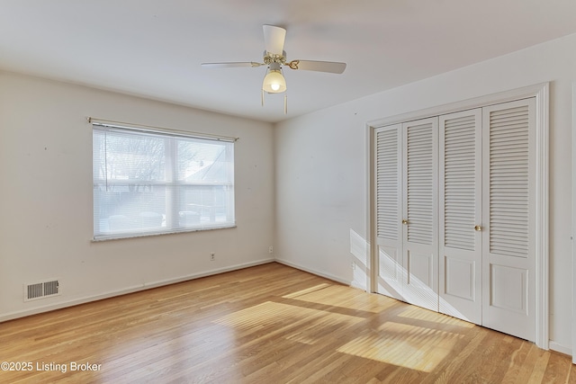 unfurnished bedroom with ceiling fan, a closet, and hardwood / wood-style floors