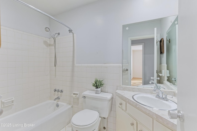 full bathroom with tile walls, toilet, vanity, and tiled shower / bath