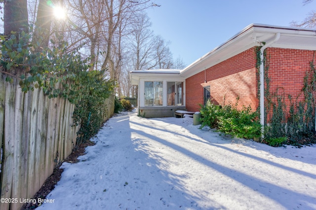 view of snowy exterior with a sunroom