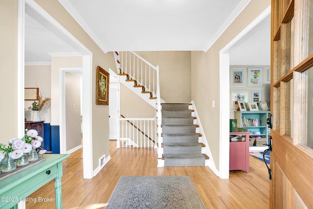 entryway with ornamental molding and hardwood / wood-style floors