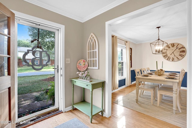 foyer featuring light wood-type flooring, crown molding, and a chandelier