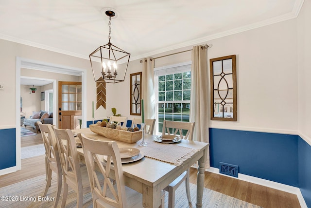 dining room with ornamental molding, light hardwood / wood-style floors, and a chandelier