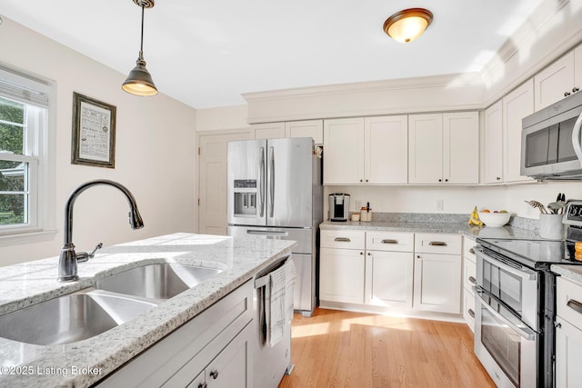 kitchen featuring stainless steel appliances, sink, white cabinets, light stone countertops, and pendant lighting