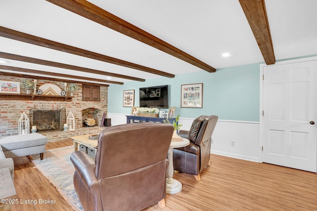 living room with a fireplace, beam ceiling, and light hardwood / wood-style floors