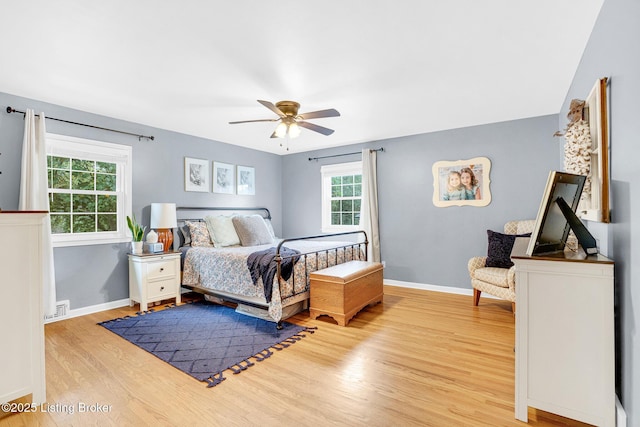 bedroom with ceiling fan, light hardwood / wood-style flooring, and multiple windows