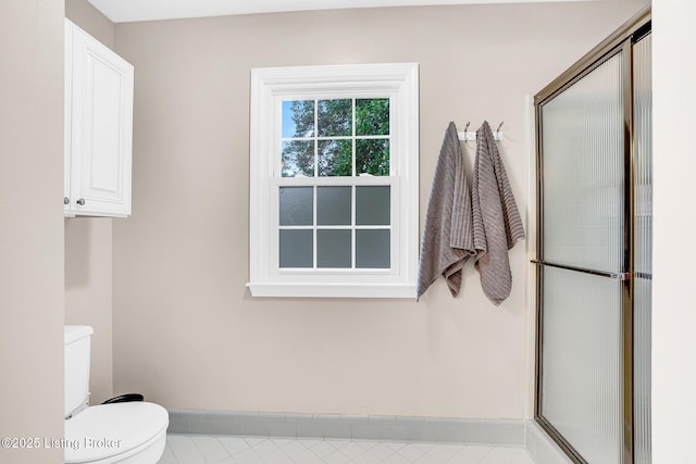 bathroom featuring toilet and a shower with door