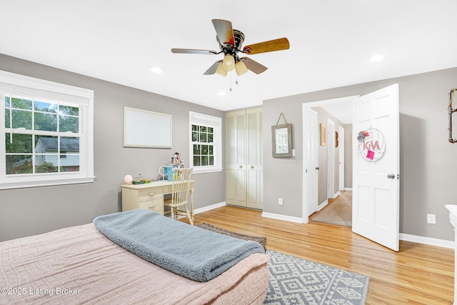 bedroom featuring hardwood / wood-style floors, a closet, ceiling fan, and multiple windows