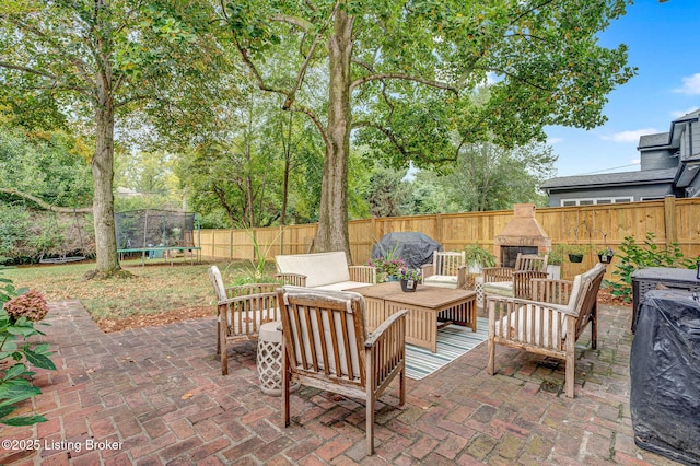 view of patio featuring a trampoline and an outdoor living space with a fireplace