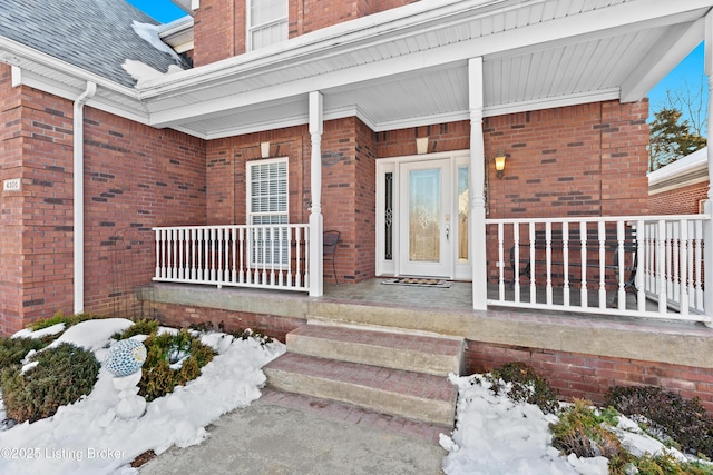 snow covered property entrance with a porch