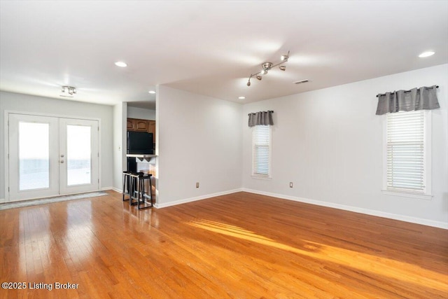 spare room featuring french doors, plenty of natural light, and hardwood / wood-style floors