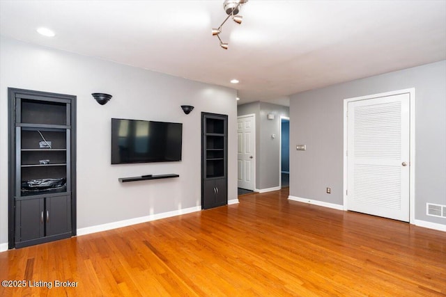 unfurnished living room featuring hardwood / wood-style floors and built in features