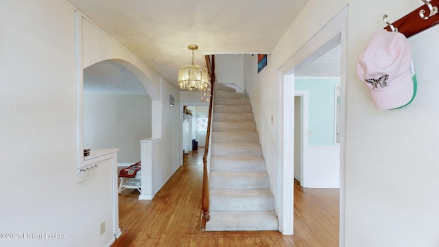 stairs featuring hardwood / wood-style flooring and an inviting chandelier