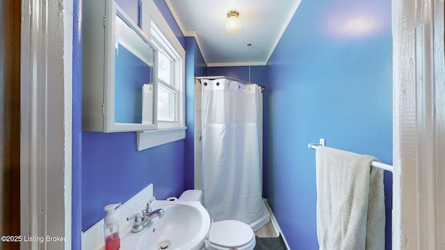 bathroom featuring sink, curtained shower, toilet, and ornamental molding