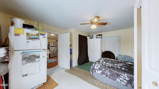 bedroom featuring ceiling fan, stainless steel fridge, white refrigerator, and a textured ceiling