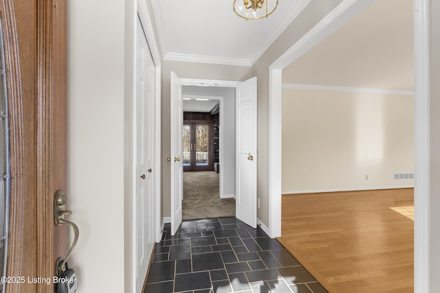 corridor with dark wood-type flooring, an inviting chandelier, and ornamental molding