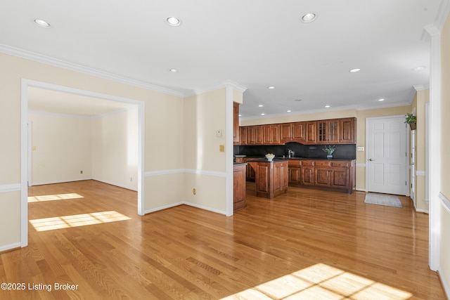 kitchen with decorative backsplash, sink, ornamental molding, and light wood-type flooring