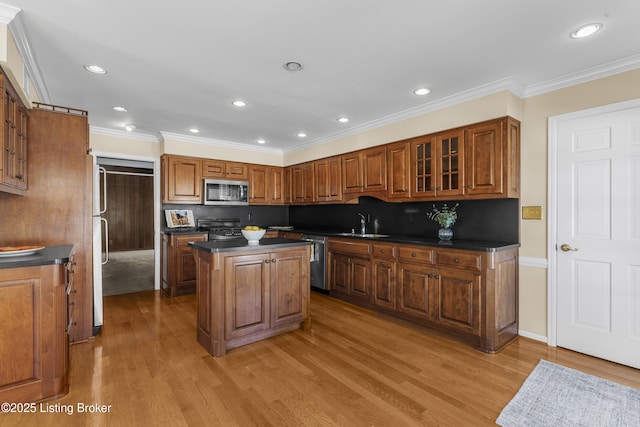 kitchen with appliances with stainless steel finishes, backsplash, a center island, crown molding, and sink