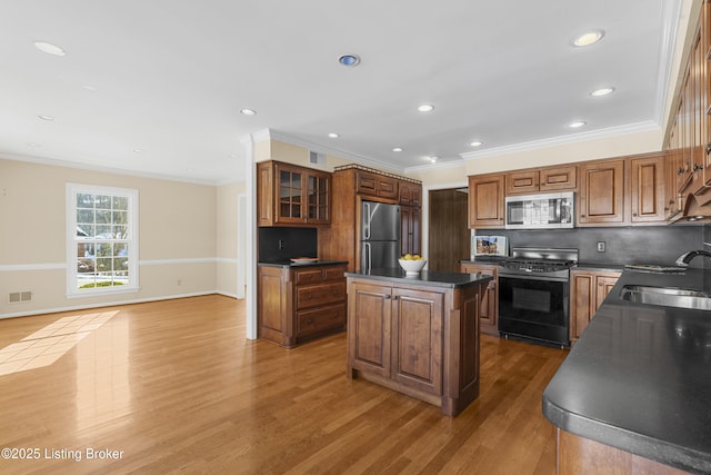 kitchen featuring stainless steel appliances, decorative backsplash, wood-type flooring, a kitchen island, and sink