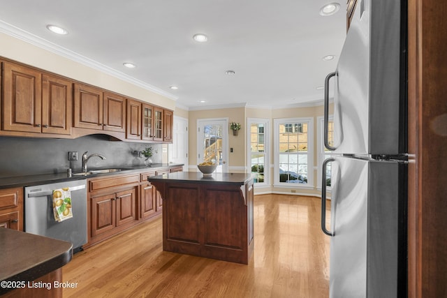 kitchen featuring stainless steel appliances, light hardwood / wood-style floors, sink, backsplash, and crown molding