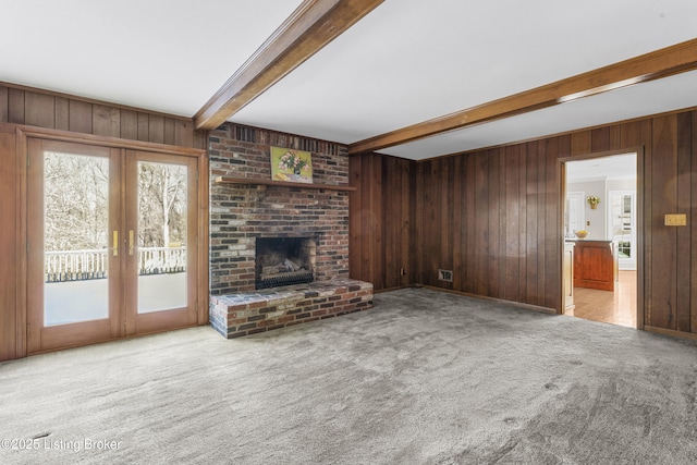 unfurnished living room with light carpet, a brick fireplace, french doors, and beamed ceiling