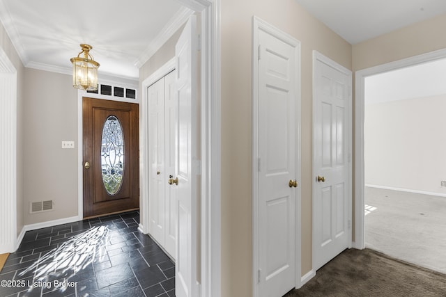 entrance foyer featuring crown molding, a chandelier, and dark colored carpet