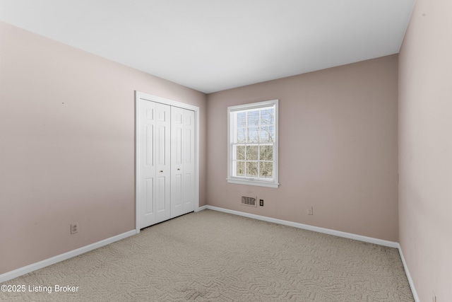 unfurnished bedroom featuring a closet and light colored carpet