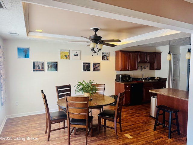 dining room featuring ornamental molding, dark wood-type flooring, ceiling fan, a tray ceiling, and sink