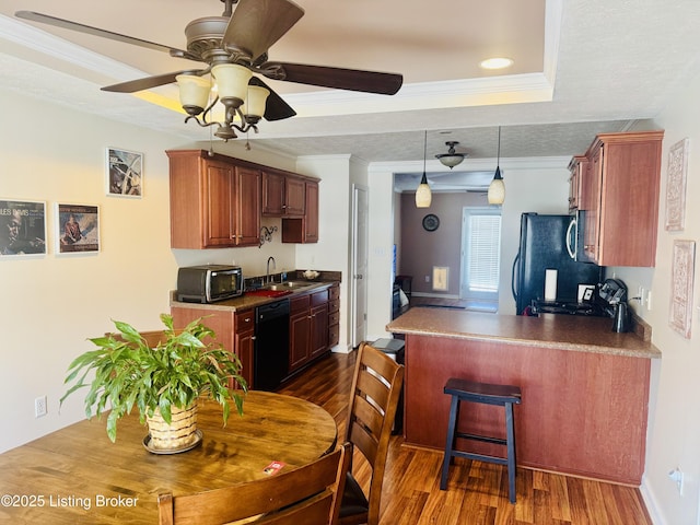 kitchen with sink, black appliances, a tray ceiling, and dark hardwood / wood-style floors