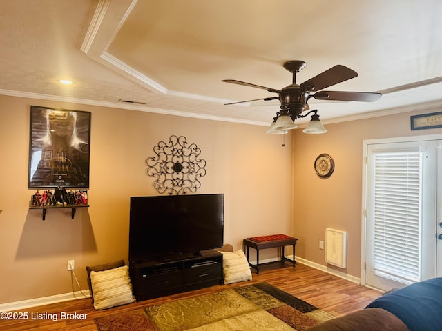 living room with wood-type flooring, ceiling fan, a tray ceiling, and crown molding