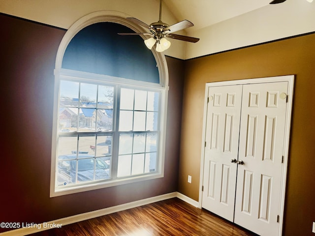 unfurnished bedroom with ceiling fan, dark hardwood / wood-style flooring, a closet, and multiple windows