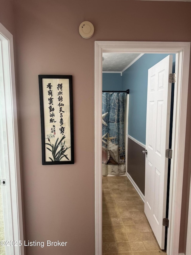 hall with a textured ceiling and crown molding