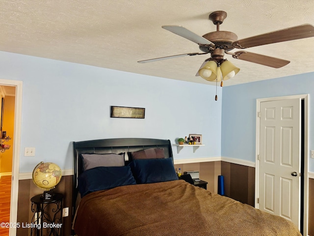 bedroom featuring a textured ceiling, ceiling fan, and wood-type flooring