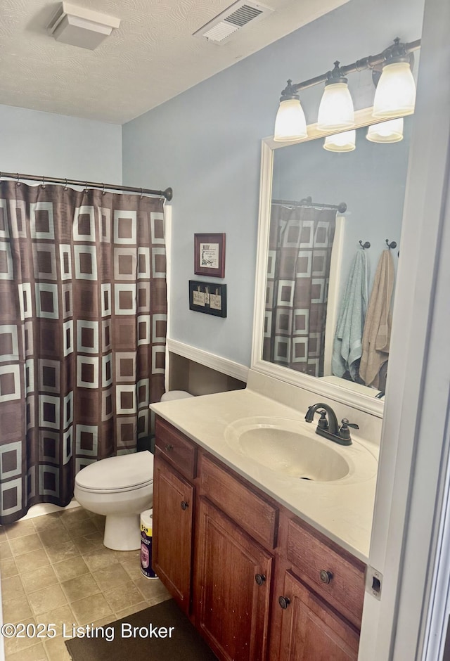 bathroom with toilet, vanity, and a textured ceiling