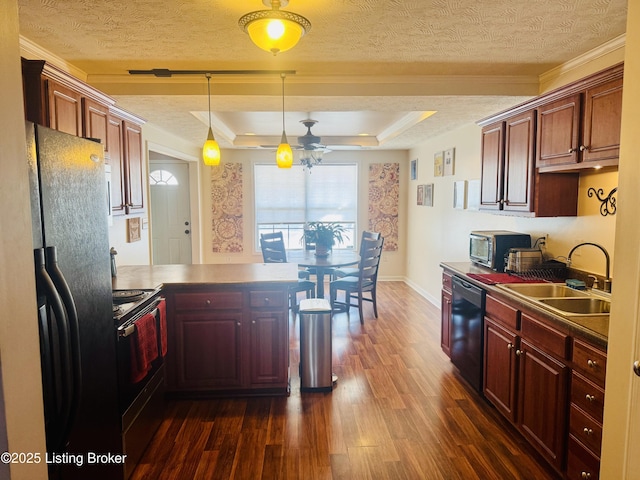 kitchen featuring kitchen peninsula, black appliances, a tray ceiling, crown molding, and sink