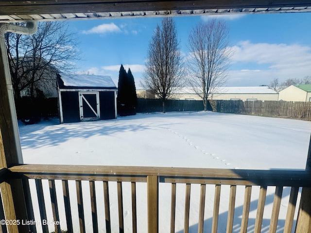 snowy yard featuring a storage unit