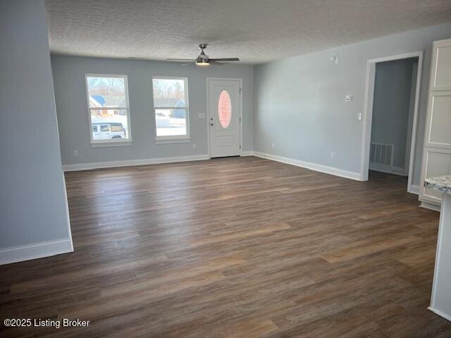 interior space featuring ceiling fan, dark wood-type flooring, and a textured ceiling