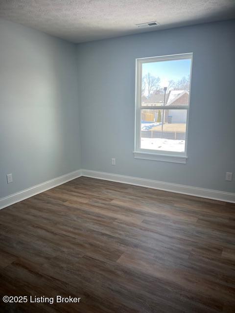 unfurnished room featuring a healthy amount of sunlight, dark wood-type flooring, and a textured ceiling