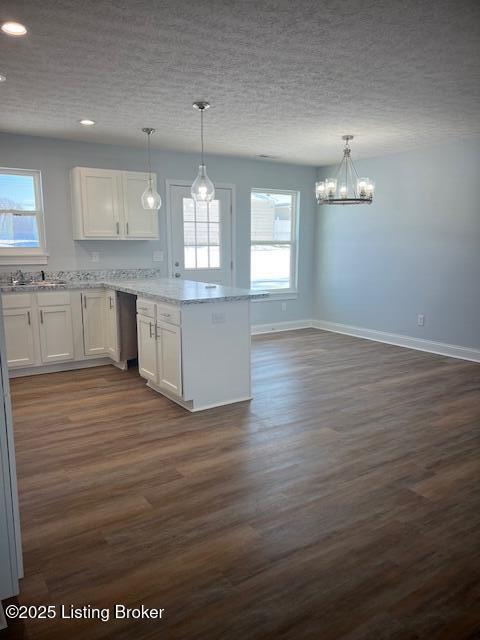 kitchen with hanging light fixtures, dark wood-type flooring, and white cabinetry