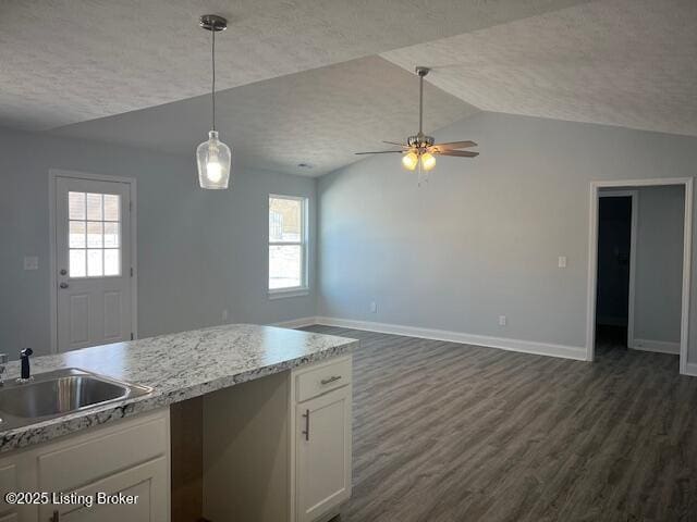 kitchen with a textured ceiling, white cabinets, decorative light fixtures, dark wood-type flooring, and sink