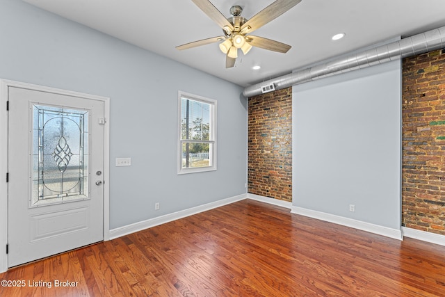 foyer with ceiling fan, brick wall, and wood-type flooring