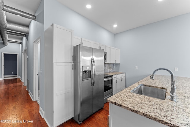 kitchen with stainless steel appliances, sink, white cabinetry, backsplash, and light stone countertops