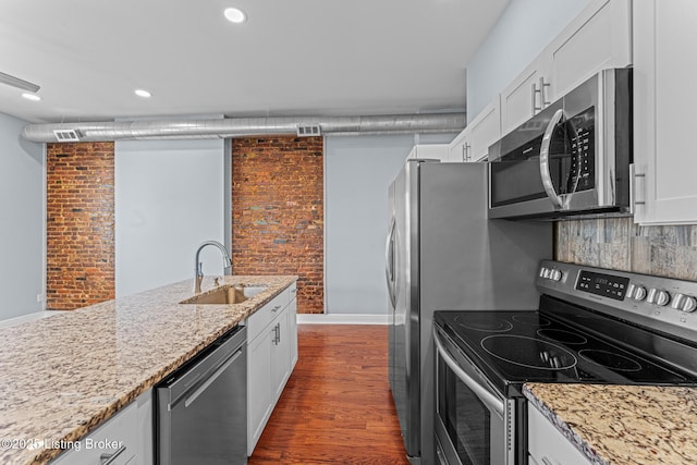 kitchen featuring appliances with stainless steel finishes, white cabinets, sink, and brick wall